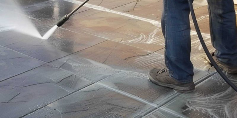A Man Using Pressure Washer on Stamped Concrete
